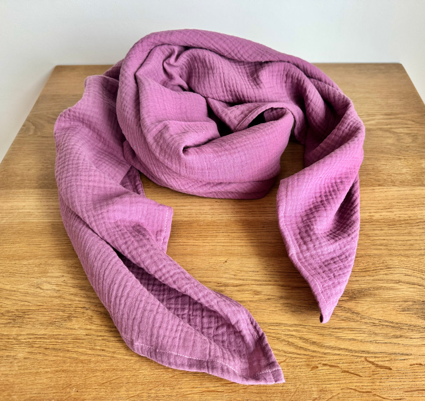 Dusty rose Pink muslin cotton scarf wrap on a wooden surface