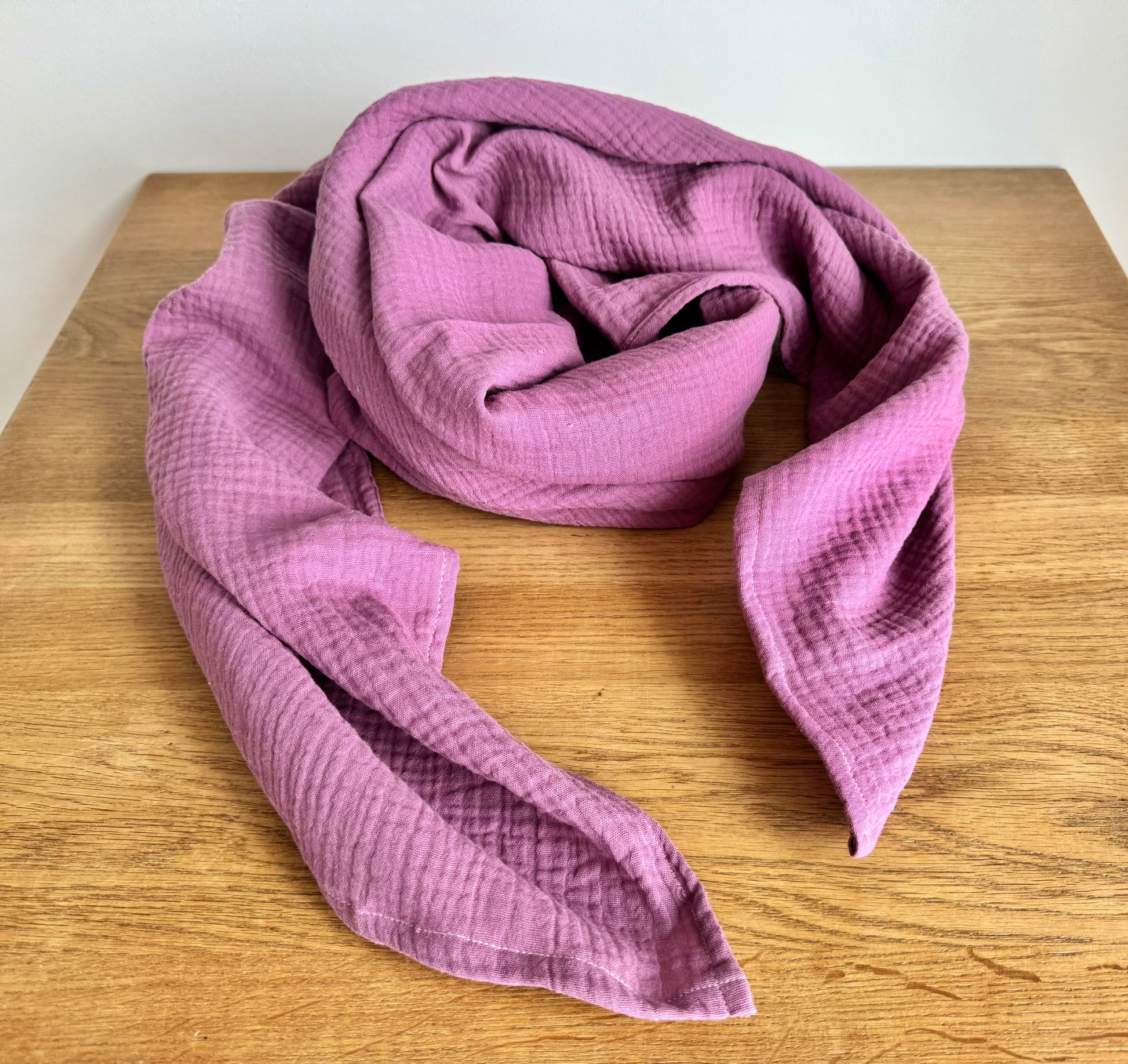 Dusty rose Pink muslin cotton scarf wrap on a wooden surface